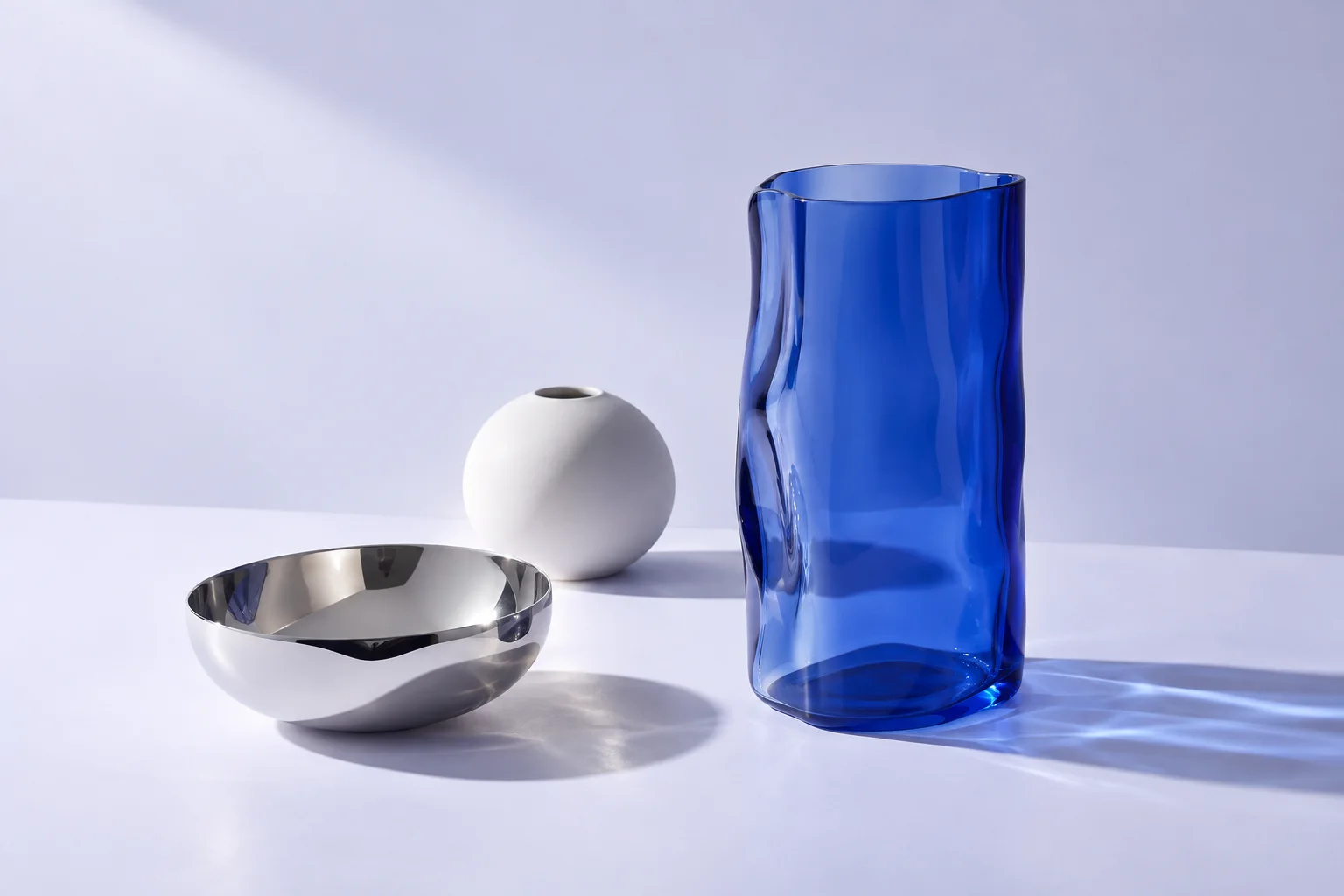 An illustrative arrangement of cobalt glass, polished silver and white porcelain objects